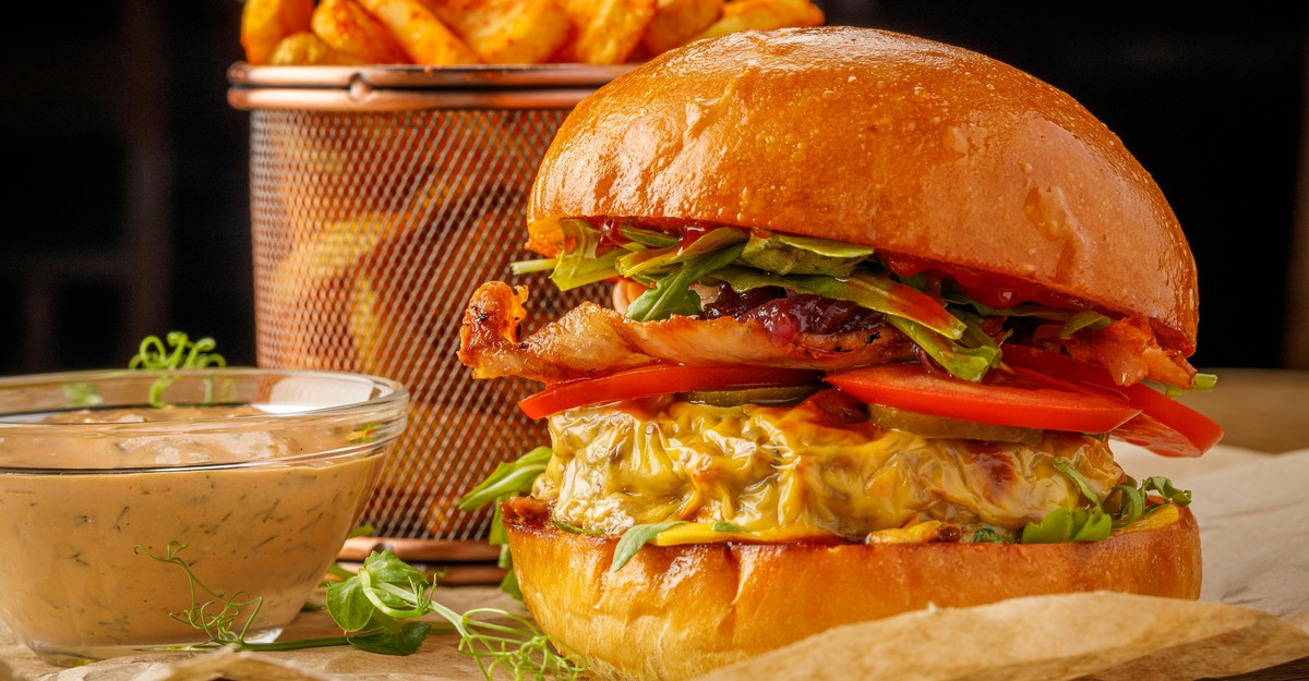 Grilled cheese hamburger with melted cheese, crisp lettuce, and ripe tomato on a brioche bun